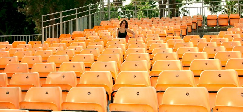 Femme assise seule au milieu de sièges vides d'un stade